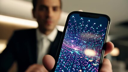 Confident businessman in black suit holding smartphone with glowing, complex digital display showing data or holographic interface, in office environment. Advanced technology and business concept. - Powered by Adobe