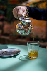 Silver oriental teapot kettle and tea cup glass to drink traditional moroccan tea in local Riad