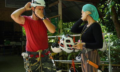 A man is assisting a woman for safety purposes before engaging ride on a zip line