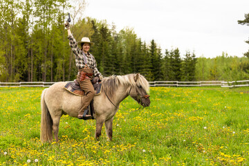 Cowgirl riding on horse (Icelandic horse). Green meadow and trees