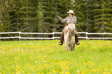 Cowgirl riding on horse (Icelandic horse). Green meadow and trees
