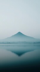 Misty Mountain Reflection in Serene Water Under a Soft Foggy Sky at Dawn in a Peaceful Landscape
