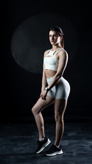 Obraz premium Athletic woman standing on black background, showing her fit body 