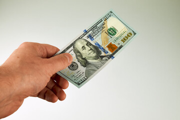 Male hand holding one new-design US $100 bill. Concept of payment, salary, cash transaction,...