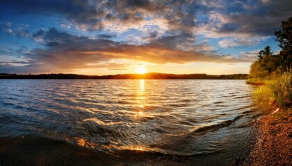 Naklejka premium tranquil sunrise over serene lake with gentle waves and dramatic sky