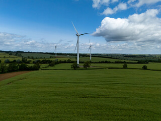 Obraz premium Wind turbines generating clean energy in green field under blue sky