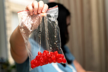 Woman's hand holding a zip-lock plastic bag with dried red berries, showcasing natural and healthy snack ingredients