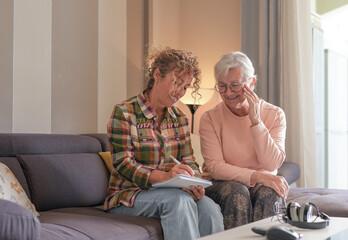 Smiling Senior woman and Caregiver Sharing a Moment sitting together on sofa at home. Concept of...