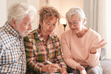 Smiling Senior couple and Caregiver Sharing a Moment sitting together on sofa at home. Concept of...
