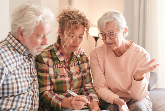 Smiling Senior couple and Caregiver Sharing a Moment sitting together on sofa at home. Concept of assistance and help to our elderly