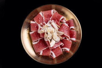 Delicate slices of raw fish and expertly prepared meat are beautifully arranged on a shimmering golden platter, highlighting culinary craftsmanship and freshness