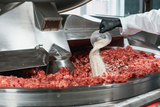 Processing of production minced meat in industrial meat grinder, close up.