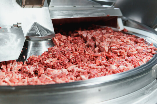 Processing of production minced meat in industrial meat grinder, close up.