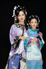 Portrait of Chinese mother and daughter dressed in Hanfu costumes on black background