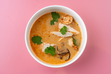 A vibrant bowl of spicy chicken soup showcases tender pieces of chicken, succulent shrimp, and fresh cilantro. The rich broth radiates warmth and flavor, inviting all to enjoy
