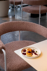 A beautifully arranged plate of pastries sits on a minimalist table in a warm-toned cafe. The inviting atmosphere invites guests to savor each bite amidst stylish decor