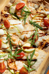 A vibrant seafood flatbread basks under golden sunlight, featuring succulent shrimp, creamy mozzarella, grape tomatoes, and fresh arugula, creating a delightful culinary masterpiece