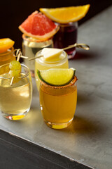 Brightly colored cocktails are elegantly displayed on a modern bar counter, each adorned with fresh fruit garnishes. The atmosphere exudes warmth and celebration, perfect for socializing