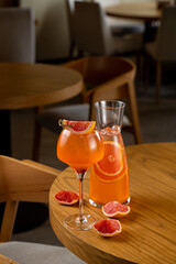 Crisp, refreshing drinks rest on a polished wooden table, garnished with vibrant citrus slices,...