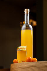 A vibrant citrus beverage is elegantly displayed alongside a bottle filled with the same refreshing drink. Juicy orange fruits enhance the inviting atmosphere, perfect for warm days