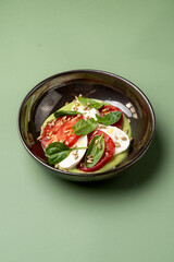 Bright colors combine in a bowl filled with ripe tomatoes, creamy mozzarella, and fresh basil leaves