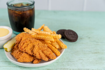 Fried chicken tenders with fries, pickle, drink and cookies 