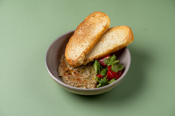 A flavorful roasted vegetable spread is beautifully presented in a bowl, accompanied by two slices...