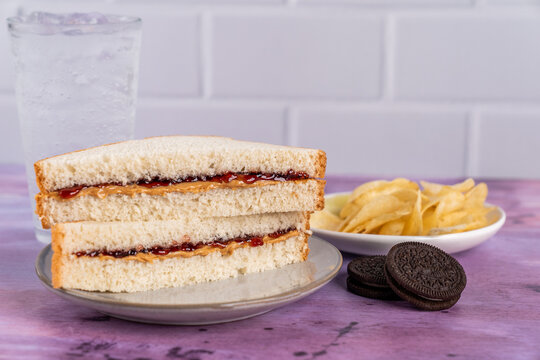 Peanut butter and jelly sandwich on white bread with chocolate sandwich cookies and chips