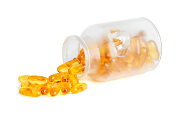 Frosted glass jar tipped over with golden fish oil softgel capsules spilling out isolated on white background.