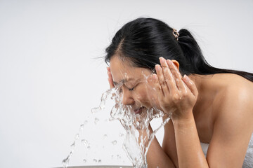 Woman washing face with clean water on white background