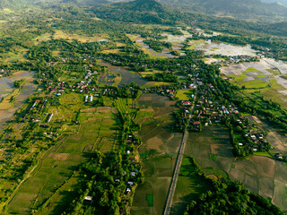 Drone aerial of farmland below forested slopes at dusk