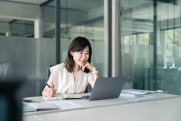 Asian mature woman using laptop computer for business studying, watching online virtual webinar training, videoconference. Focused saleswoman businesswoman working in office, writing notes. Copy space