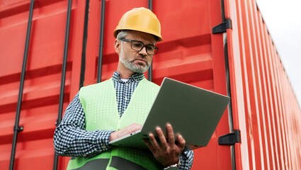 Portrait of successful focused supervisor of freight transportation company standing in vest and...