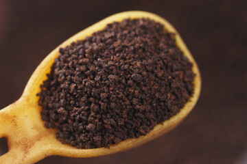 Dark ground coffee in a wooden spoon ready for brewing