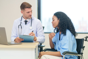 doctor in white gown with stethoscope,asking a woman patient on wheelchair a present illness and writing paper on clipboard to diagnosis and treatment