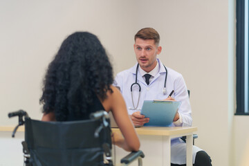doctor in white gown with stethoscope,asking a woman disabled person on wheelchair for present...