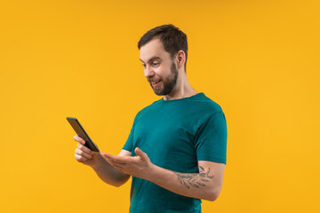 Studio shot of happy smiling bearded man reading message notificationon his smartphone with excited face expression glad to get good news