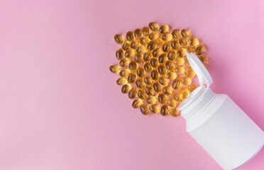 Omega capsules with fish oil with white bottle on the pink background.