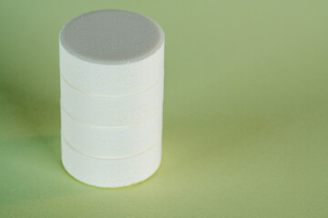 Staple of four white vitamin medicine tablets on light green pastel color background