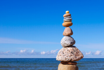 High Rock zen pyramid of grey and pink stones on a background of blue sky and sea