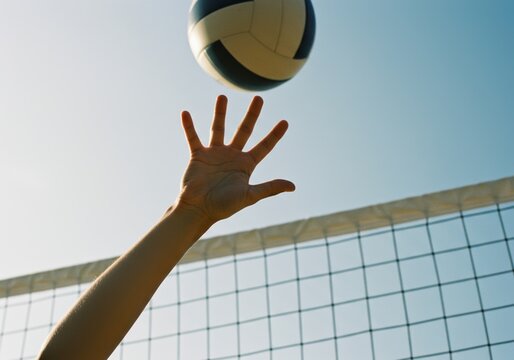 Beach volleyball player's hand reaching for ball near net under clear sky
