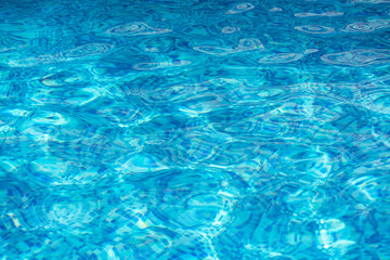 Close-up of shimmering blue pool water reflecting sunlight, creating a tranquil summer scene. Perfect for themes of leisure, childhood, and sporty summer vibes.