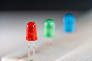 Focused red LED light emitting diode in science kit next to green and blue diodes stuck in...