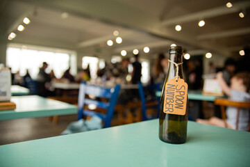 Handwritten Tag on Bottle in Crowded Restaurant Scene