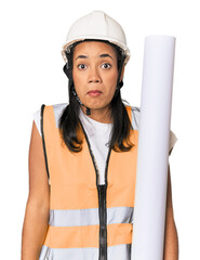 Young Filipino female architect shrugs shoulders and open eyes confused.