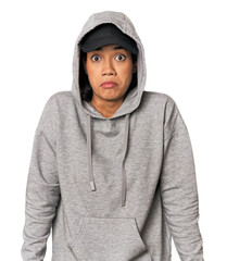 Young Filipino woman in studio shrugs shoulders and open eyes confused.