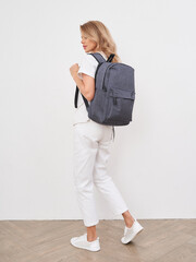 Blonde woman modeling a stylish backpack in a modern studio setting
