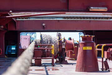Large mooring winch on a ship's deck, featuring thick, braided ropes wound around a cylindrical metal drum. 