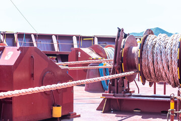 Large mooring winch on a ship's deck, featuring thick, braided ropes wound around a cylindrical metal drum. 