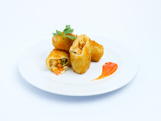 Crispy vegetable risol cut open on a white plate, served with chili sauce. isolated on white background